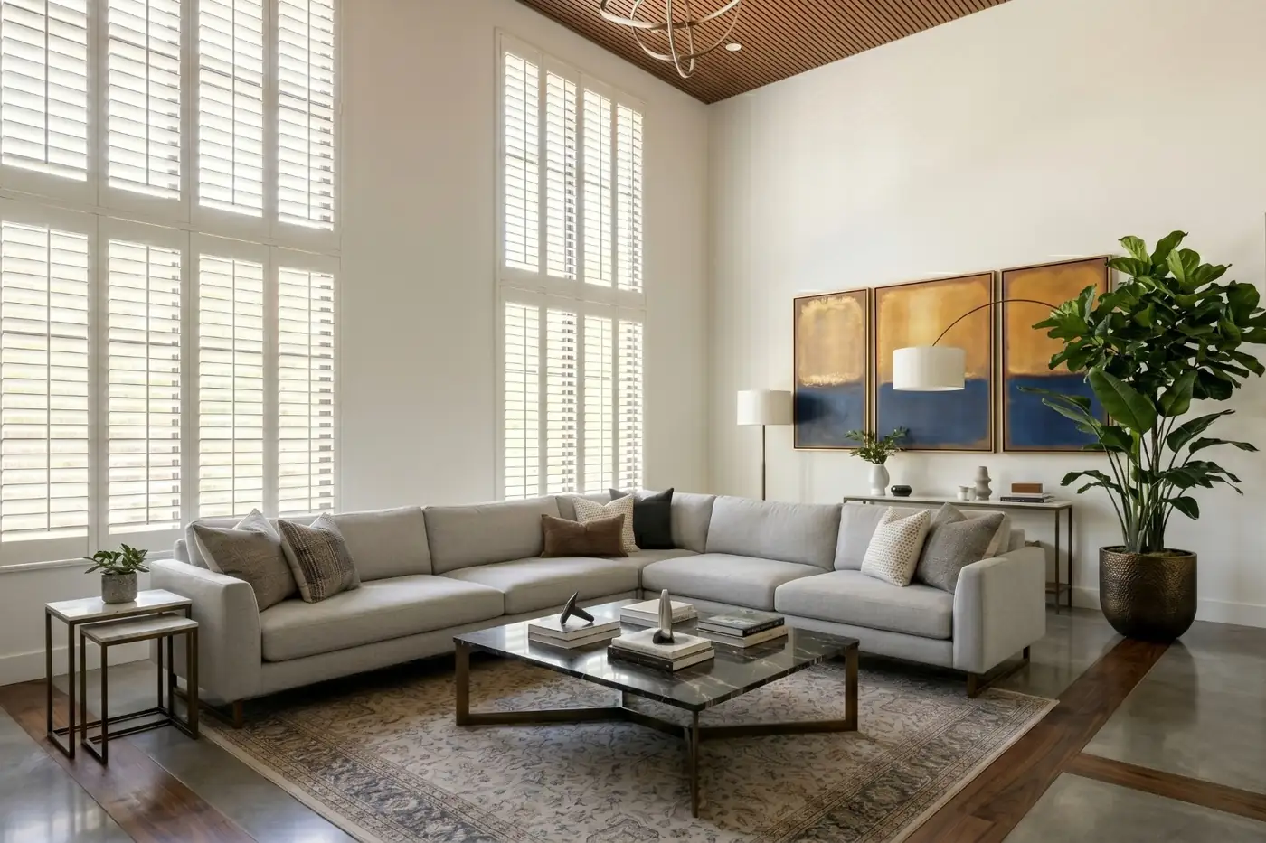 Floor-to-ceiling white faux wood shutters on tall windows in a two-story Arizona living room | Southwest Blinds and Shutters
