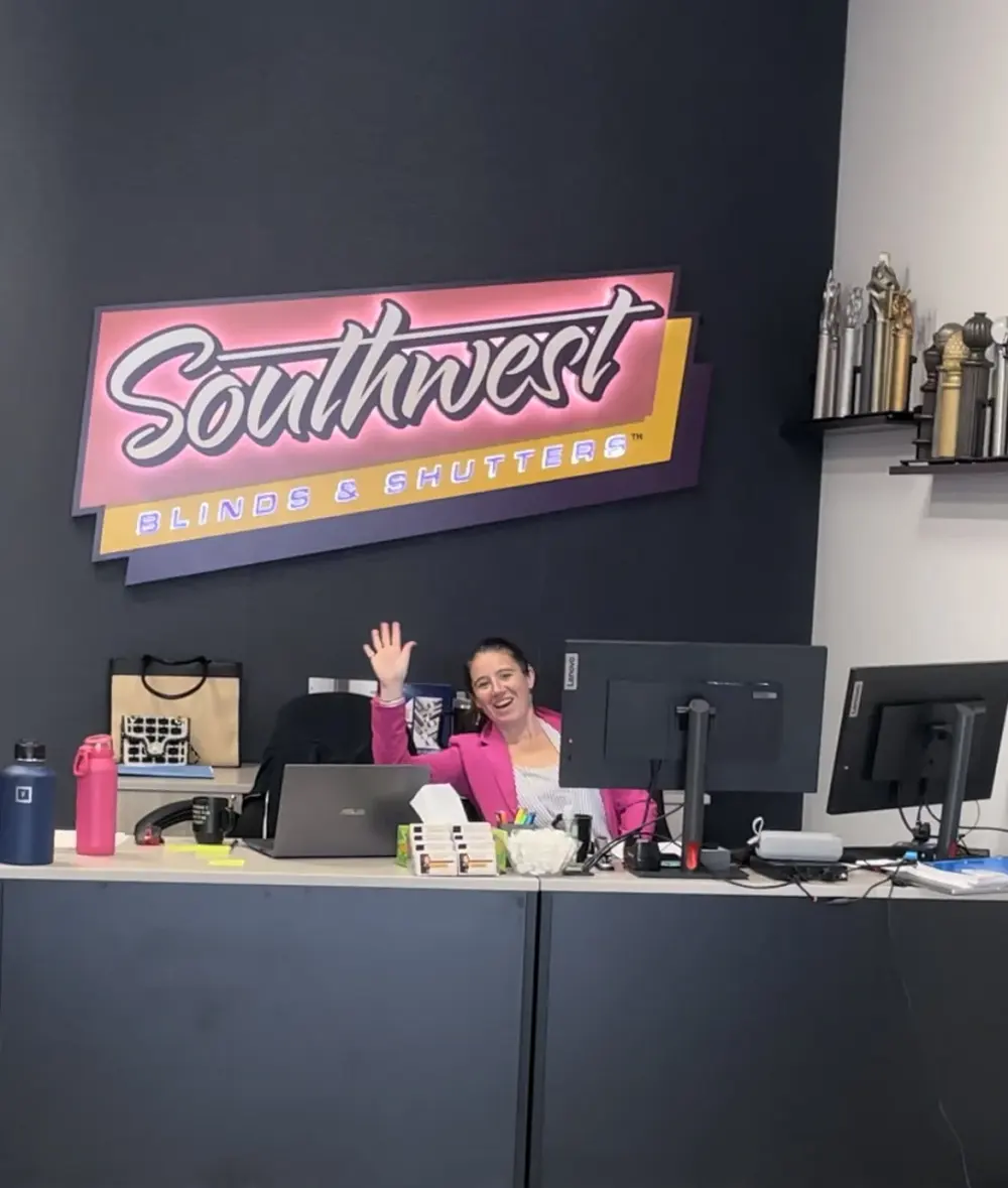 Showroom Lead Stephanie waving to the camera from behind the desk
