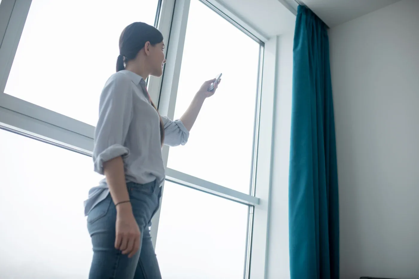 Focused Woman Using A Gadget For Opening The Shades