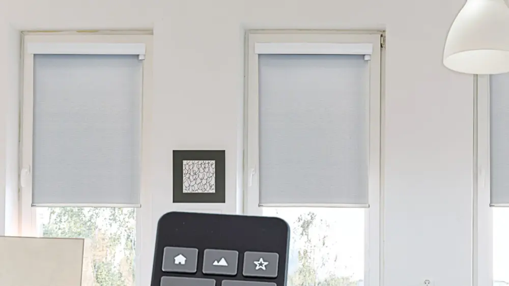 Two motorized off-white window shades installed on small windows