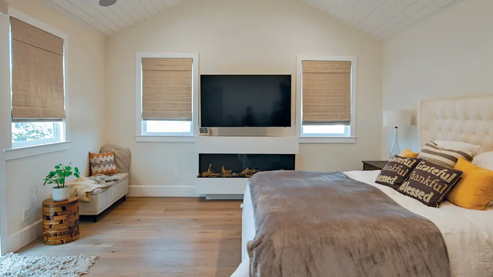 Cozy bedroom with tan-colored walls and fabric shutters on the windows