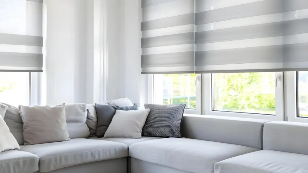 Modern living room couch with a window behind it, with a beautiful gray roller window shade on it.