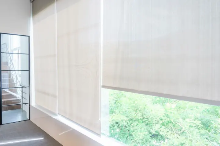 Bright room with white motorized shades covering large windows