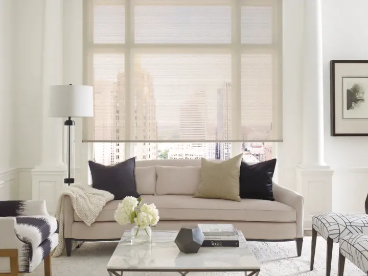 Opaque roller window shades in a living room with tan furniture and a marble table