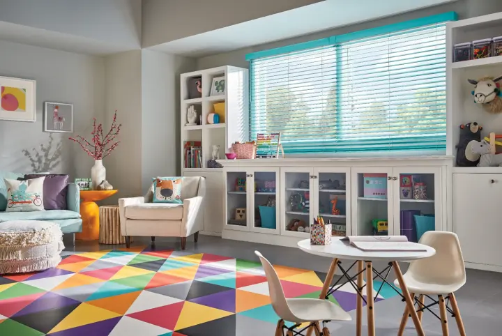 A bright room with colorful carpeting and blue blinds.