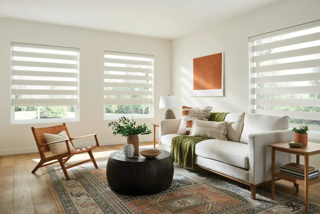 A bright living room with white banded sheer shades on three windows