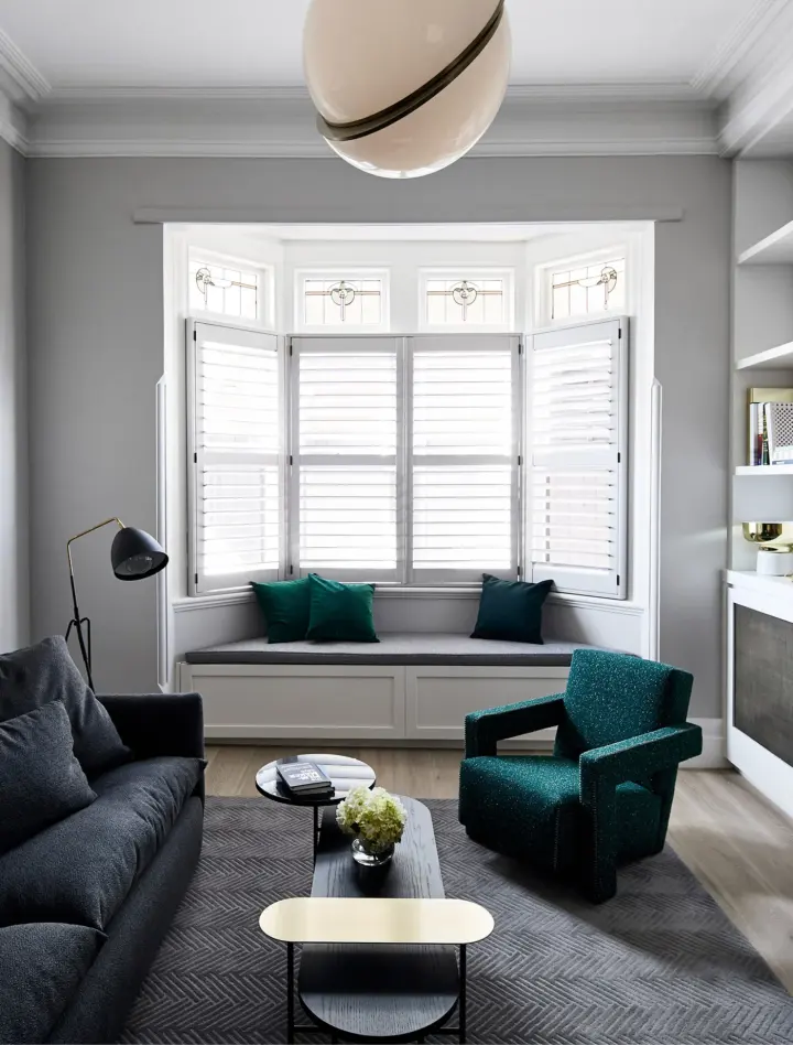 White window shutters on bay window in front of sitting area in the home