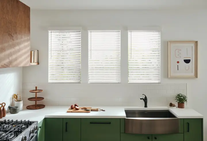 Bright living room with desert-smart window blinds, wide sunlit windows, modern seating, accent décor, and warm filtered natural light.