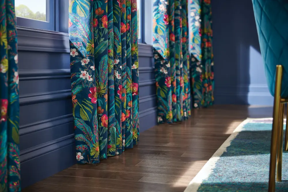 Close-up focusing on the detail of the design on green drapery next to flowers.