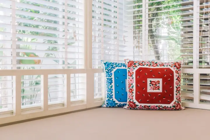 White shutters in nook with quilted red and blue throw pillows