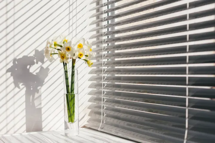 Window blinds with vase of flowers in foreground in Las Vegas | Southwest Blinds and Shutters