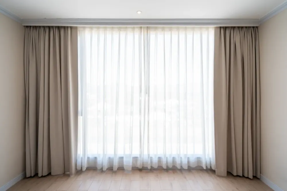 Expert custom drapery layered over a window in a bedroom
