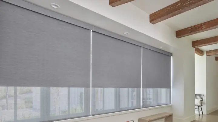 Angled view of grey roller window shades in a home with a white interior