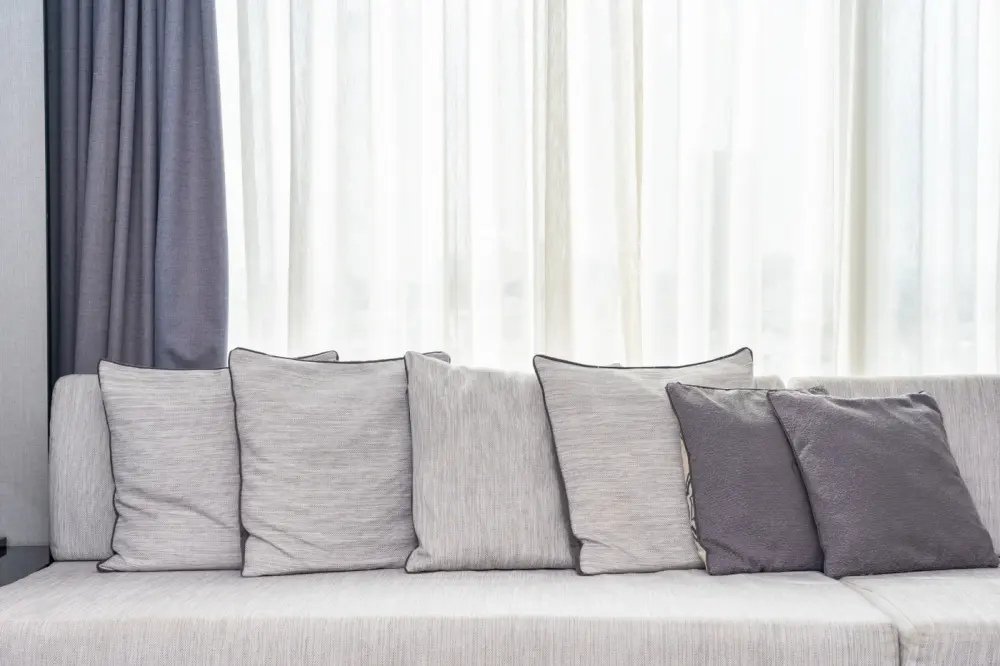 Sheer drapery with purple drapes on large window to match couch