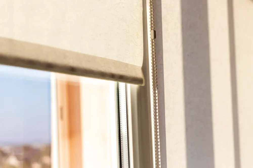 Close-up view of roller window shades with beaded string for closing and opening.