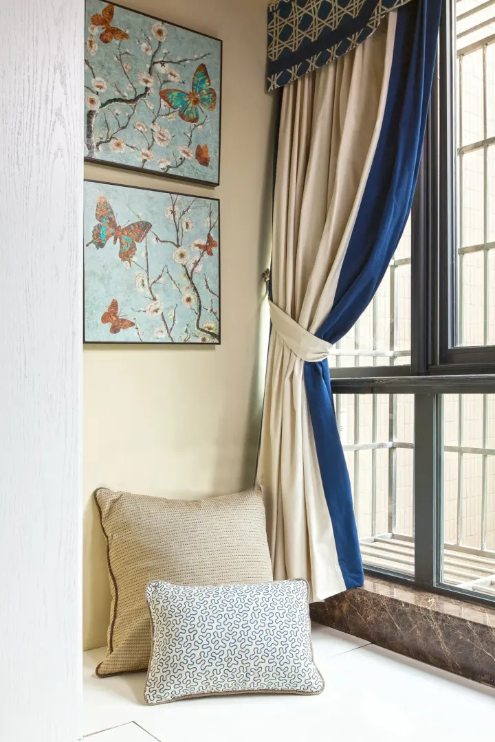 Cozy sitting nook in a Las Vegas, NV home with thick blue and cream-colored drapery over a window. Butterfly art is hanging on the wall.