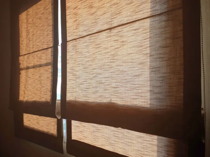 Tan Roman shades over a window