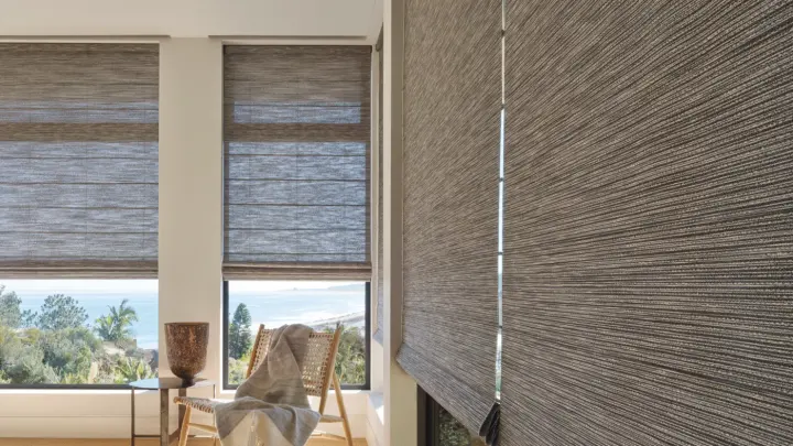 Four large windows with brown fabric shades on them