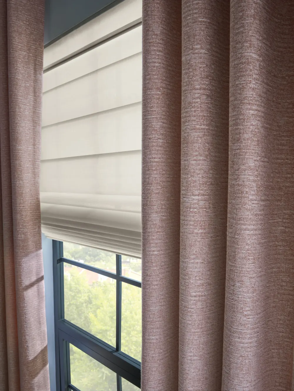 A close-up of layered custom drapery paired with a Roman shade
