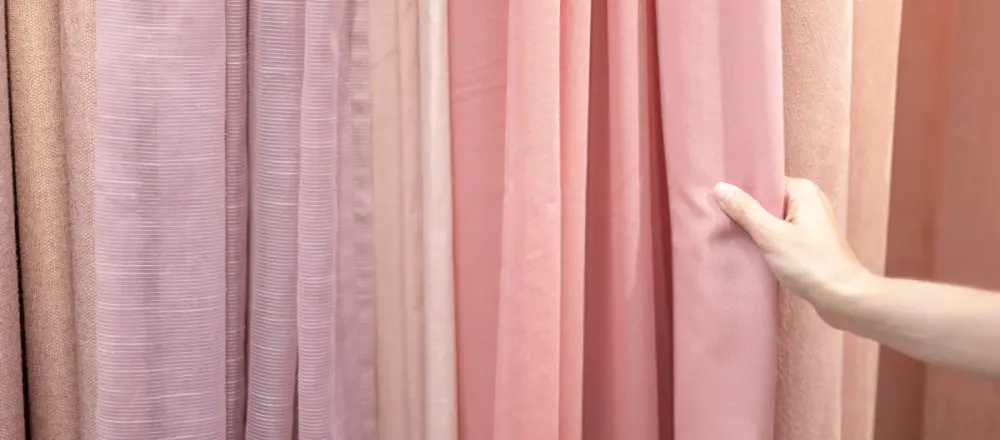 A hand examining different drapery fabrics for quality in Gilbert, AZ.