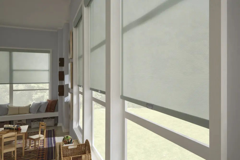 An image of a sunroom with light-filtering roller window shades on tall windows, providing soft daylight control.
