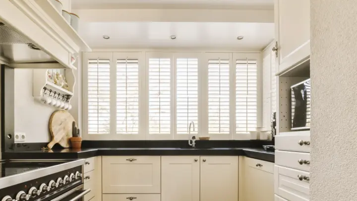 White indoor shutters over kitchen windows in a modern kitchen.