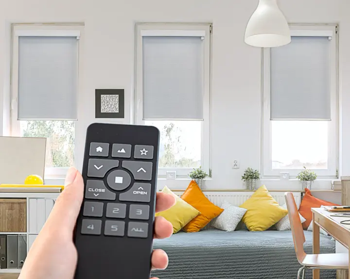A homeowner uses a remote to control the motorized shades in their living room.