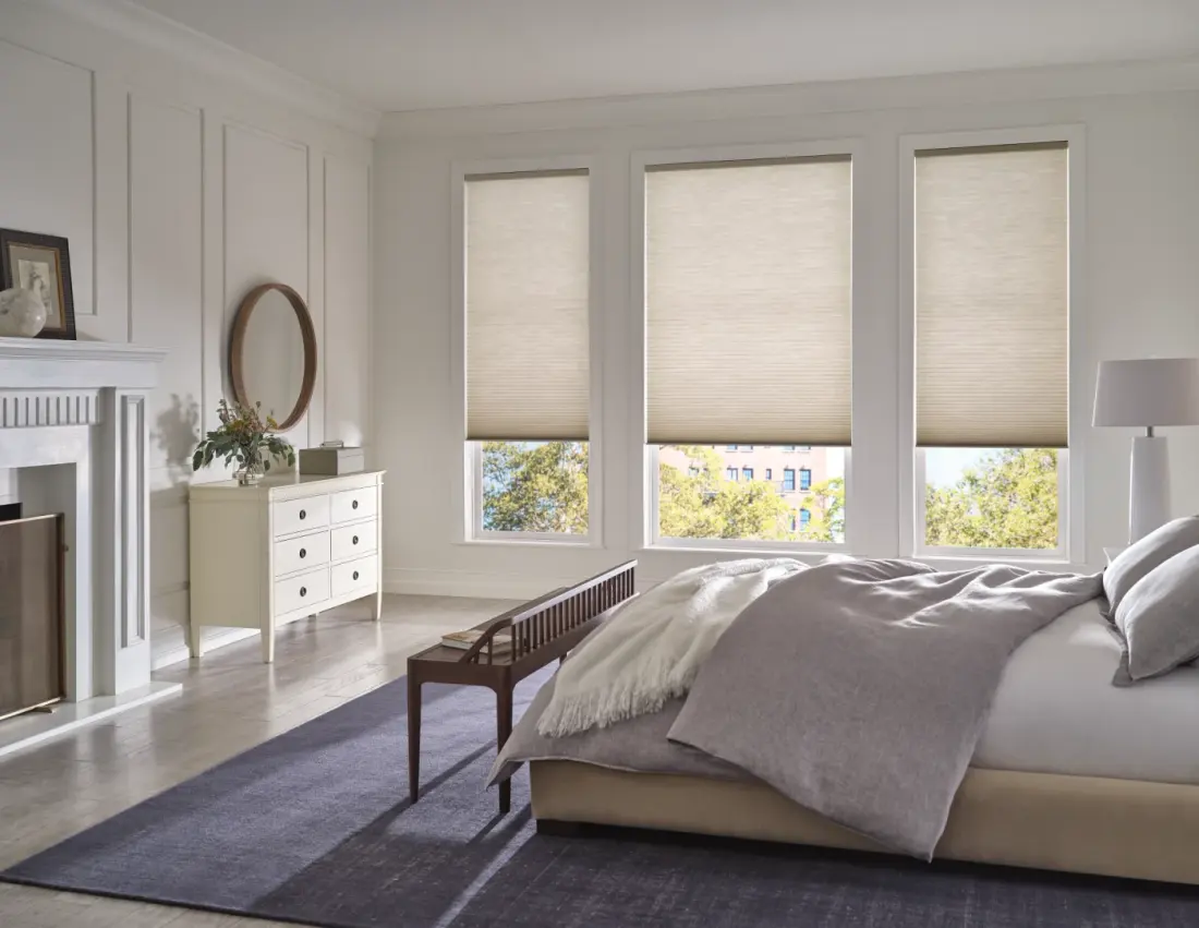 A relaxing bedroom with window shades blocking the sunlight over three windows.