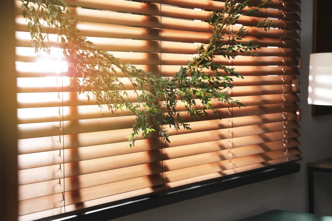 Beautiful Garland Made Of Eucalyptus Branches Hanging On Window Blinds Indoors