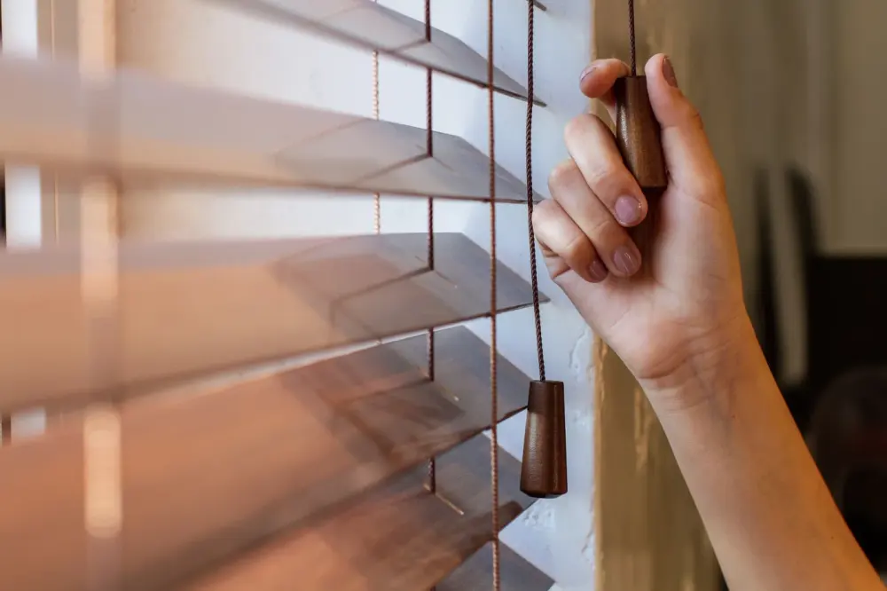 Close up on a hand pulling the cord on window blinds