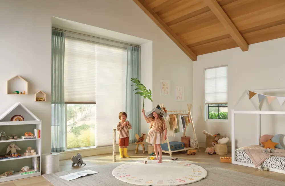A spacious playroom with white window shades over the window, with children playing.