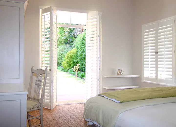 Image of a bedroom with white door and window shutters