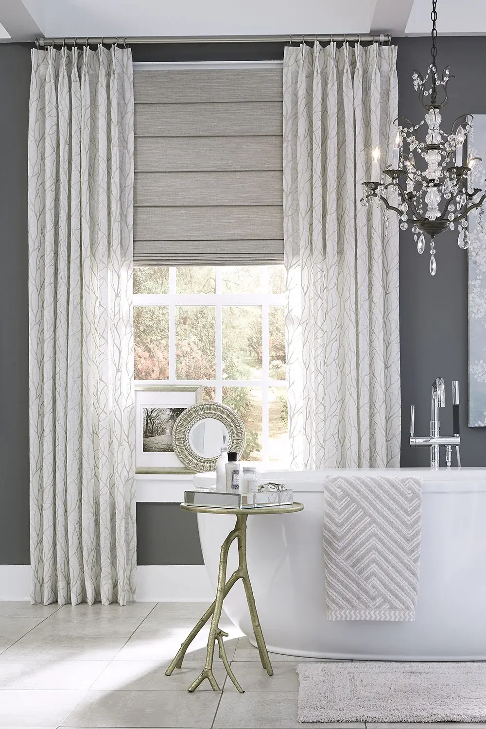 A bathroom with a standalone tub and elegant drapes over a gray shade.