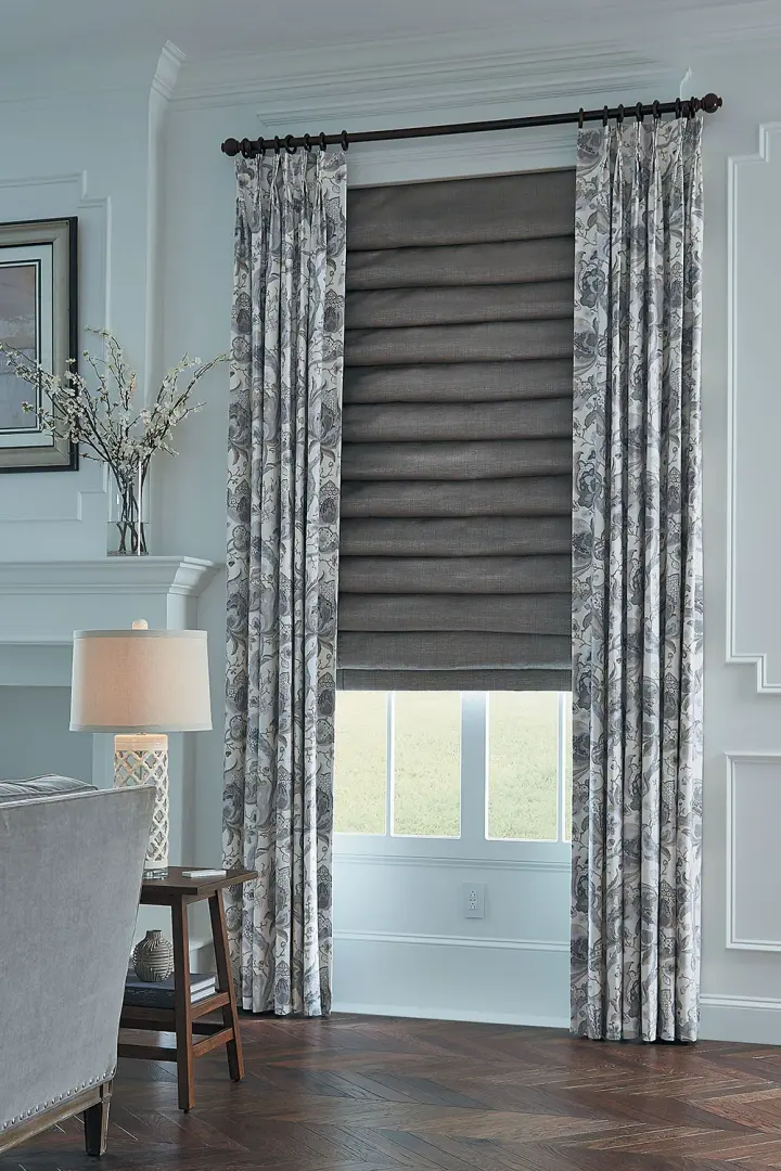 Gray-patterned drapery panels over gray shades.