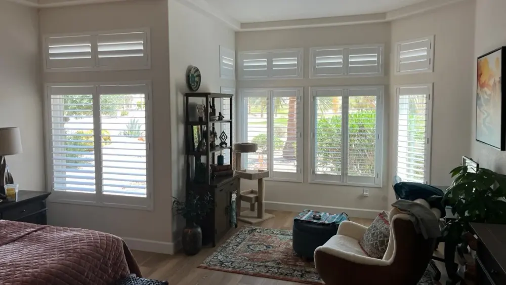 White plantation shutters with matching transom shutters in a bedroom corner