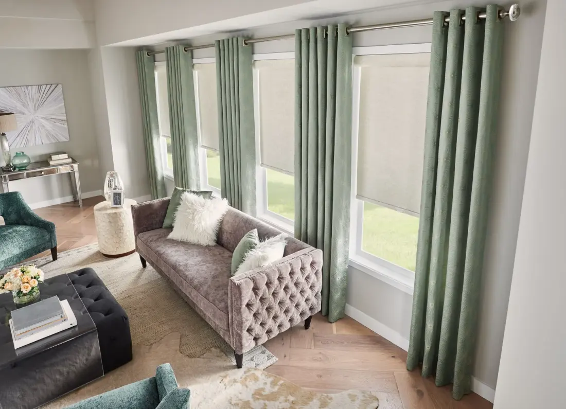 A living room with green drapery layered over white shades.