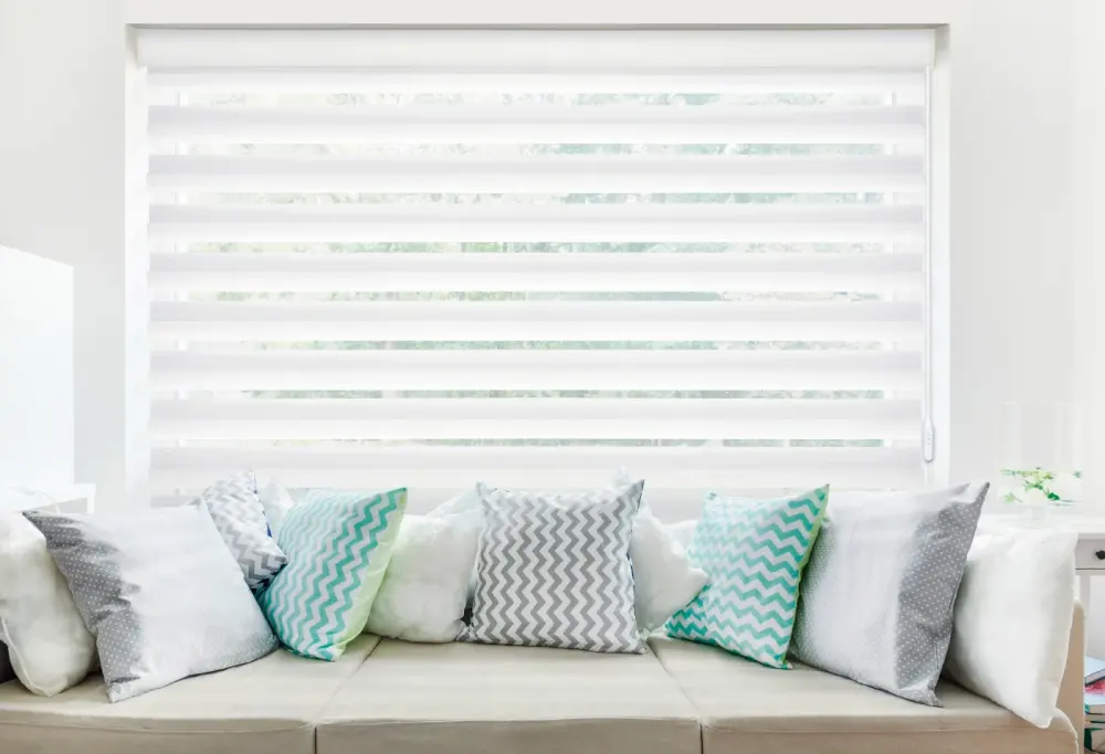 Sheer motorized shades on a window behind a couch.