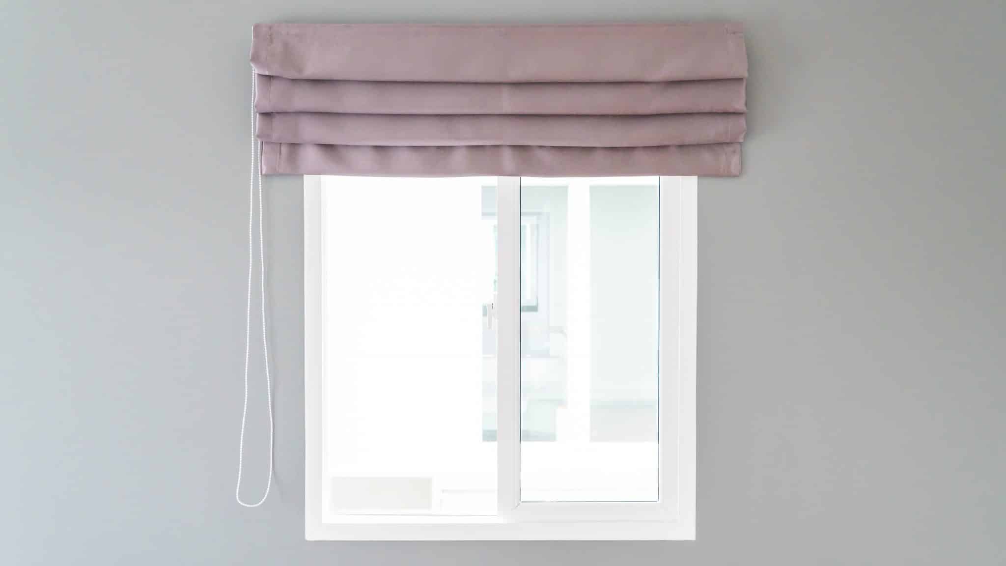 A Window With A Pink Shade With Multiple Folds In It