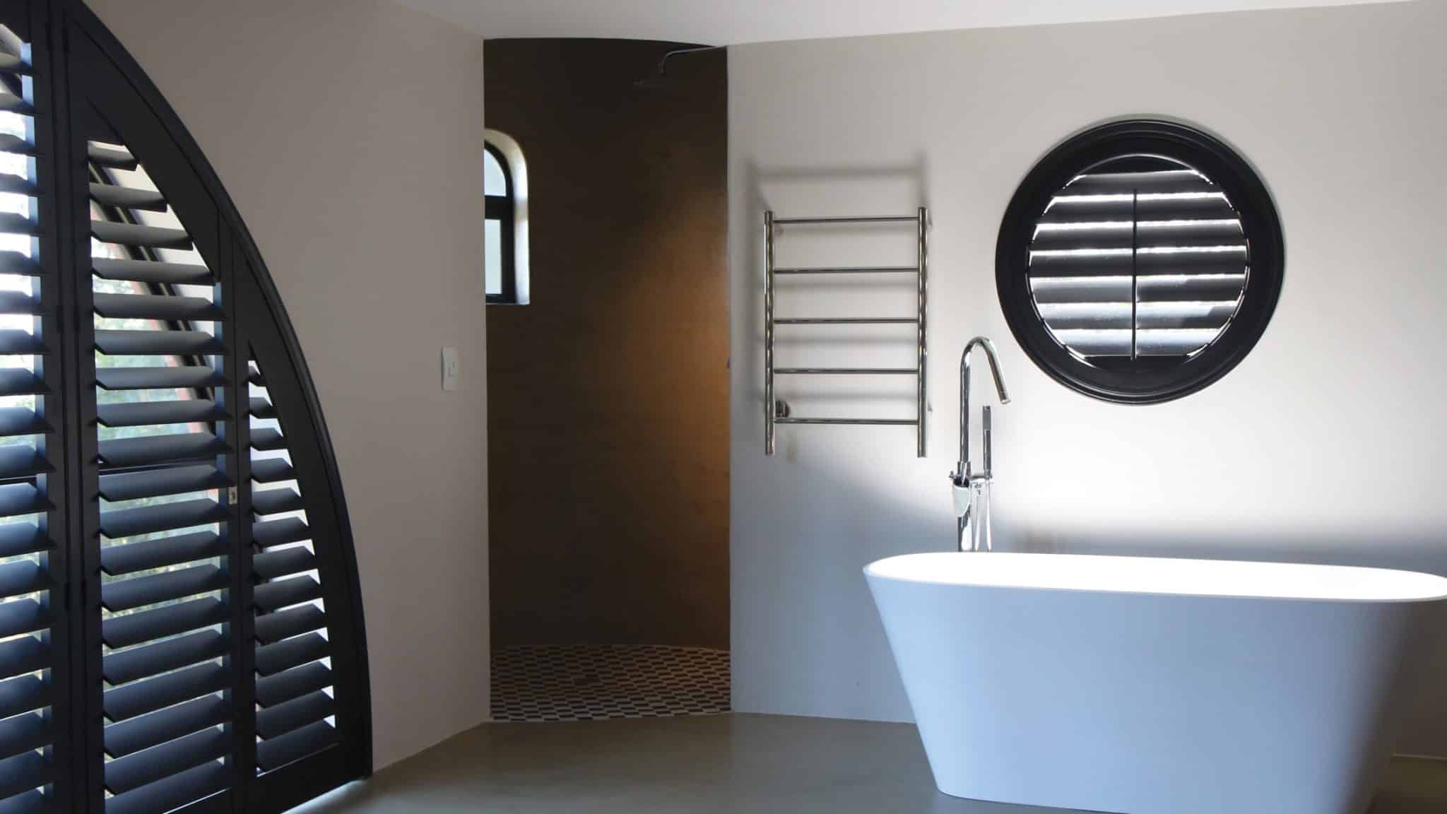 Darkened Bathroom With White Bathtub, White Interior, With Black Custom-Fit Shutters